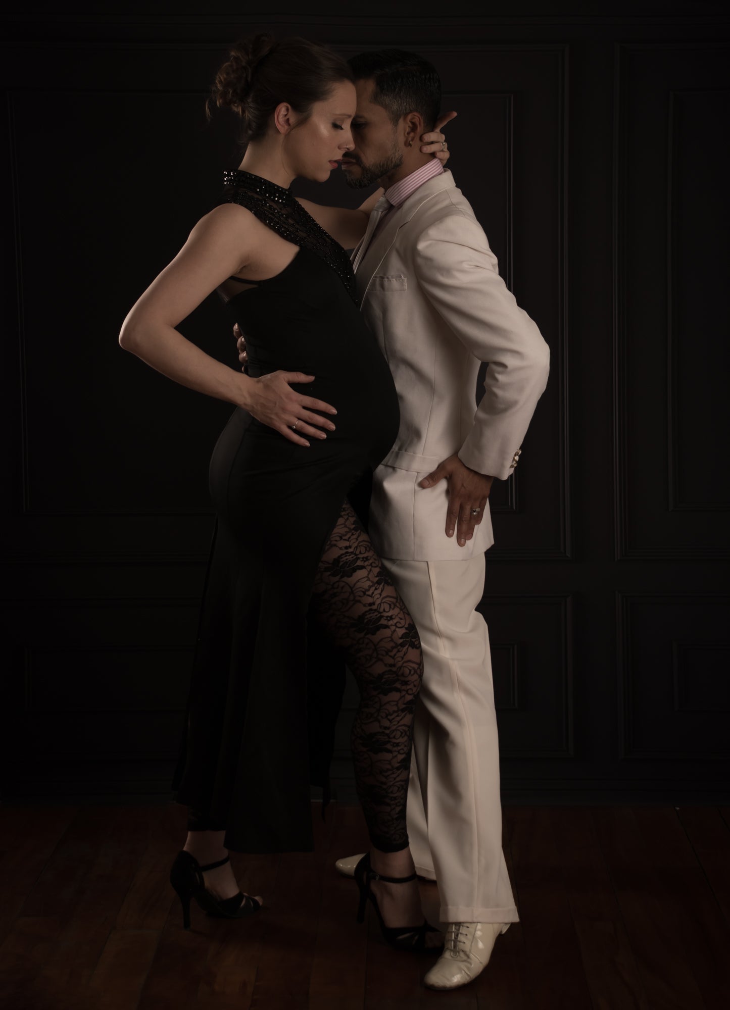 Two people in formal attire posing against a dark background