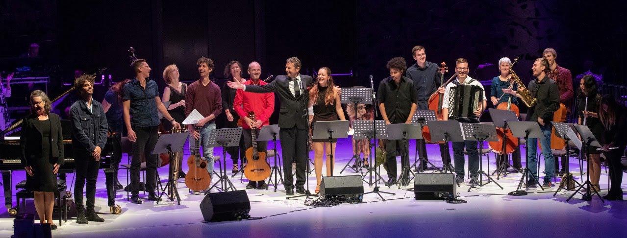 Group of musicians on stage with instruments and sheet music