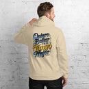 Person wearing a beige hoodie with text on the back against a white brick wall.