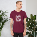 Man wearing a maroon t-shirt with Spanish text, standing against a light gray background with plants.