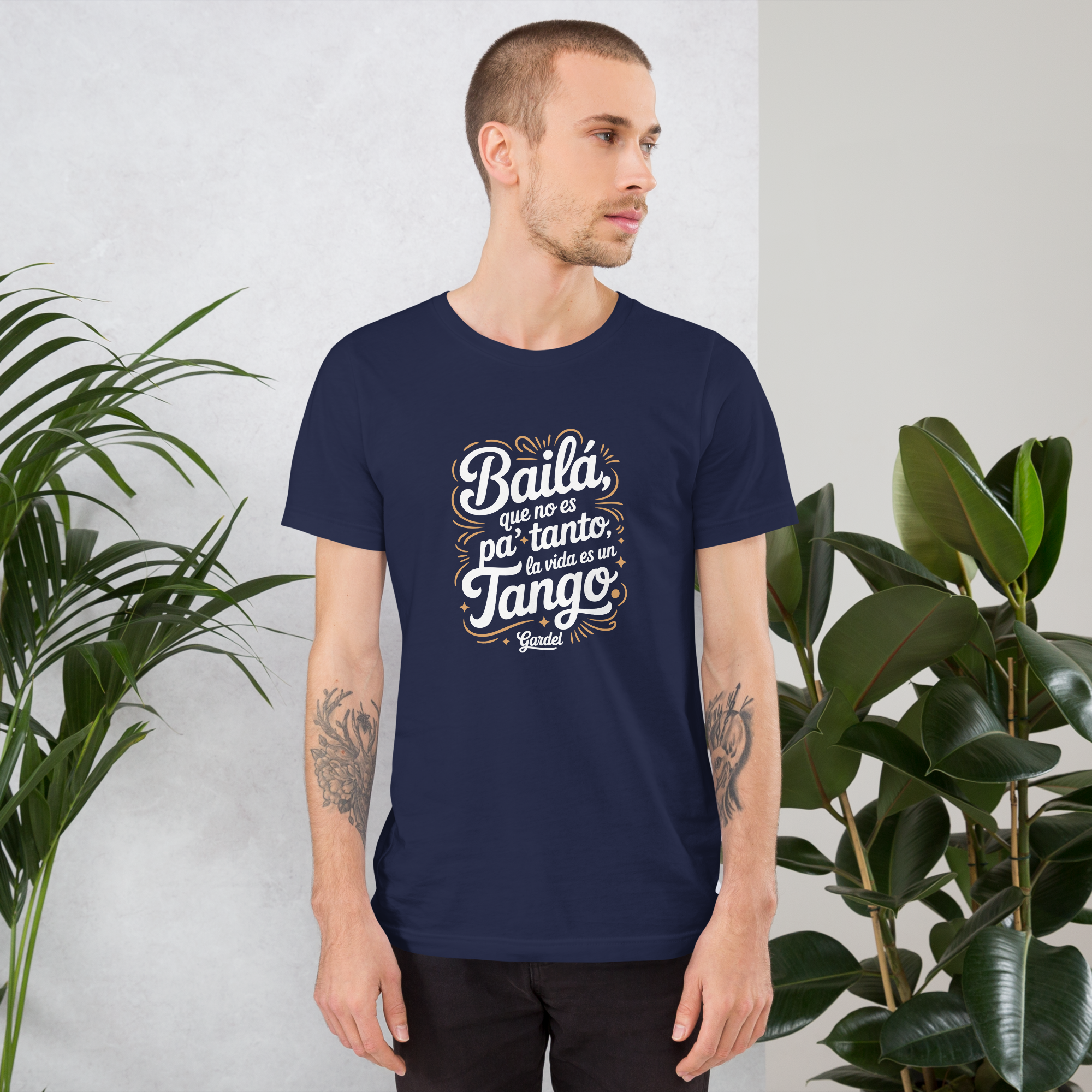 Man wearing a navy blue t-shirt with white text standing in front of plants.