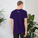 Man wearing a purple t-shirt with text on the back, standing against a light gray wall with plants.