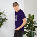 Man wearing a purple t-shirt with text, standing between two potted plants against a white wall.