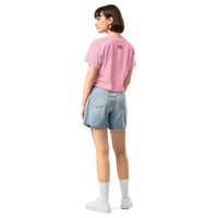 Person wearing a pink t-shirt and denim shorts on a white background